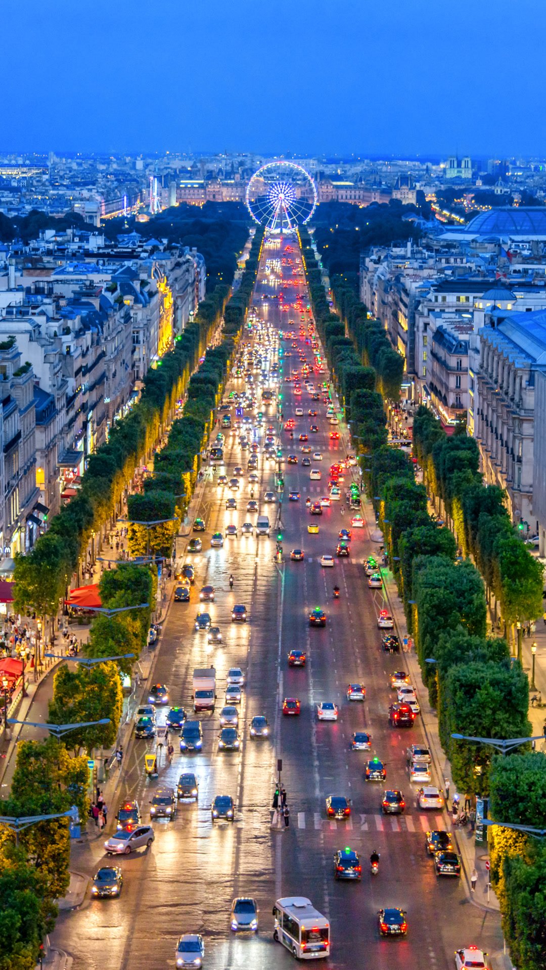 The Champs-Élysées at dusk, wet with traffic, the Ferris wheel at the end of the avenue.